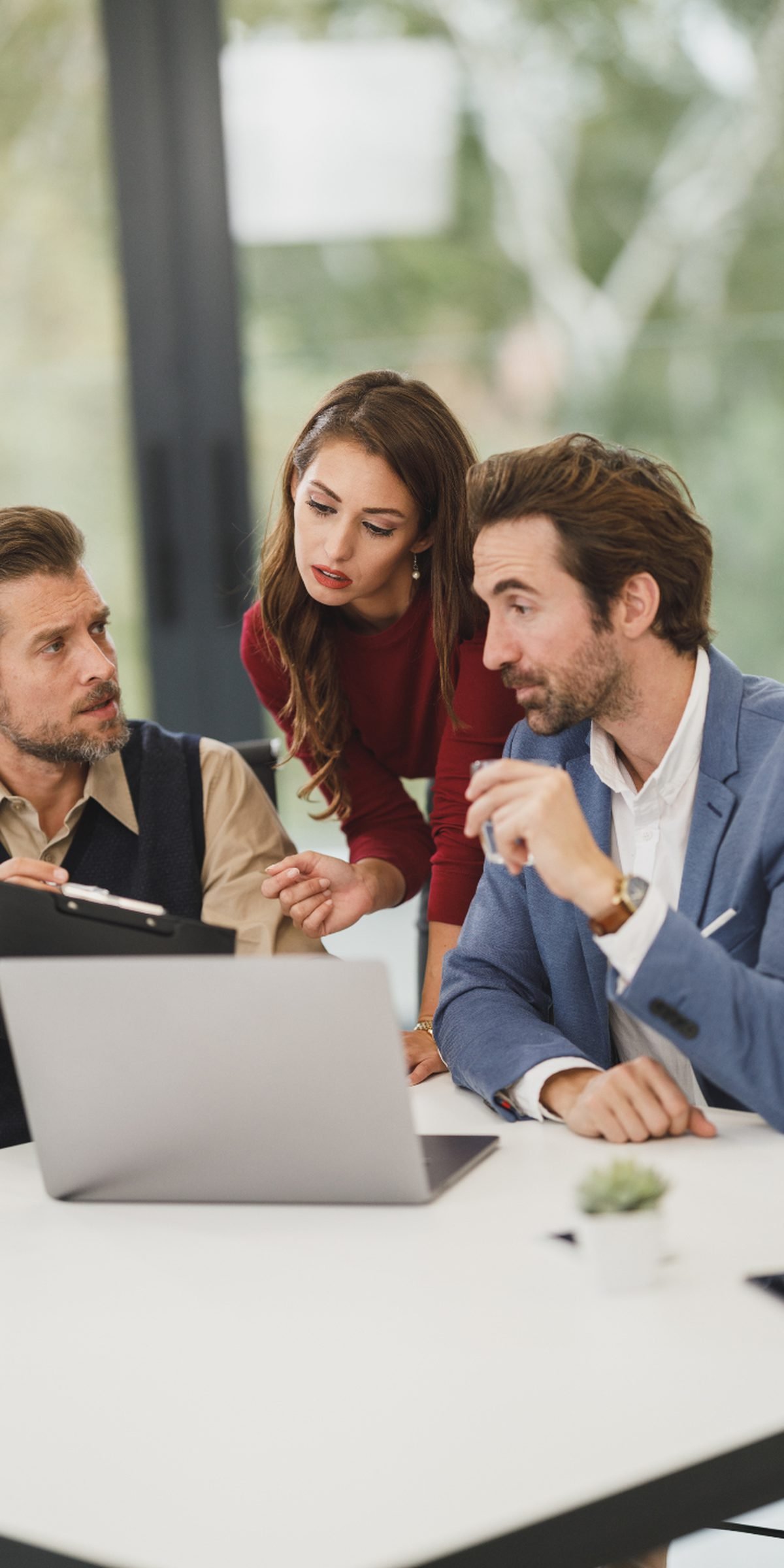 Three colleagues talking around a laptop during a working session
