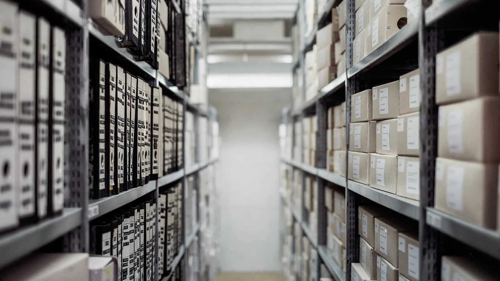 Rows of archive shelving packed with labelled document boxes — the certification paperwork building surveyor automation is built to handle