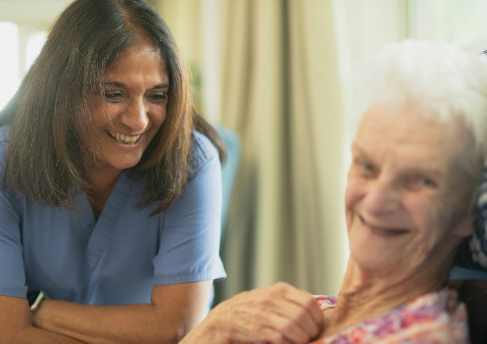 Aged care worker smiling warmly with an older resident during a home visit