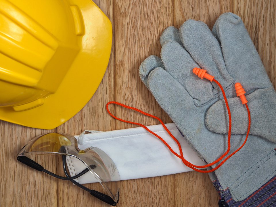 Yellow hard hat, work gloves and rolled drawings laid out on a timber workbench