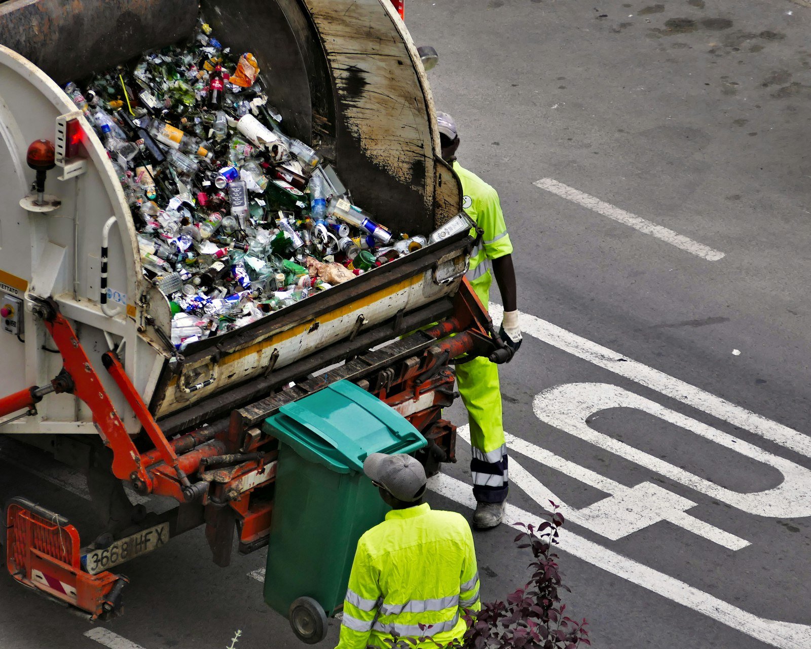 Waste collection worker in high-visibility clothing loading a bin into a kerbside collection truck in Melbourne
