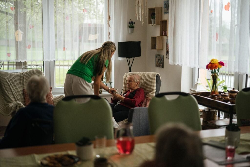 Carer serving tea to residents in the lounge of an aged care home