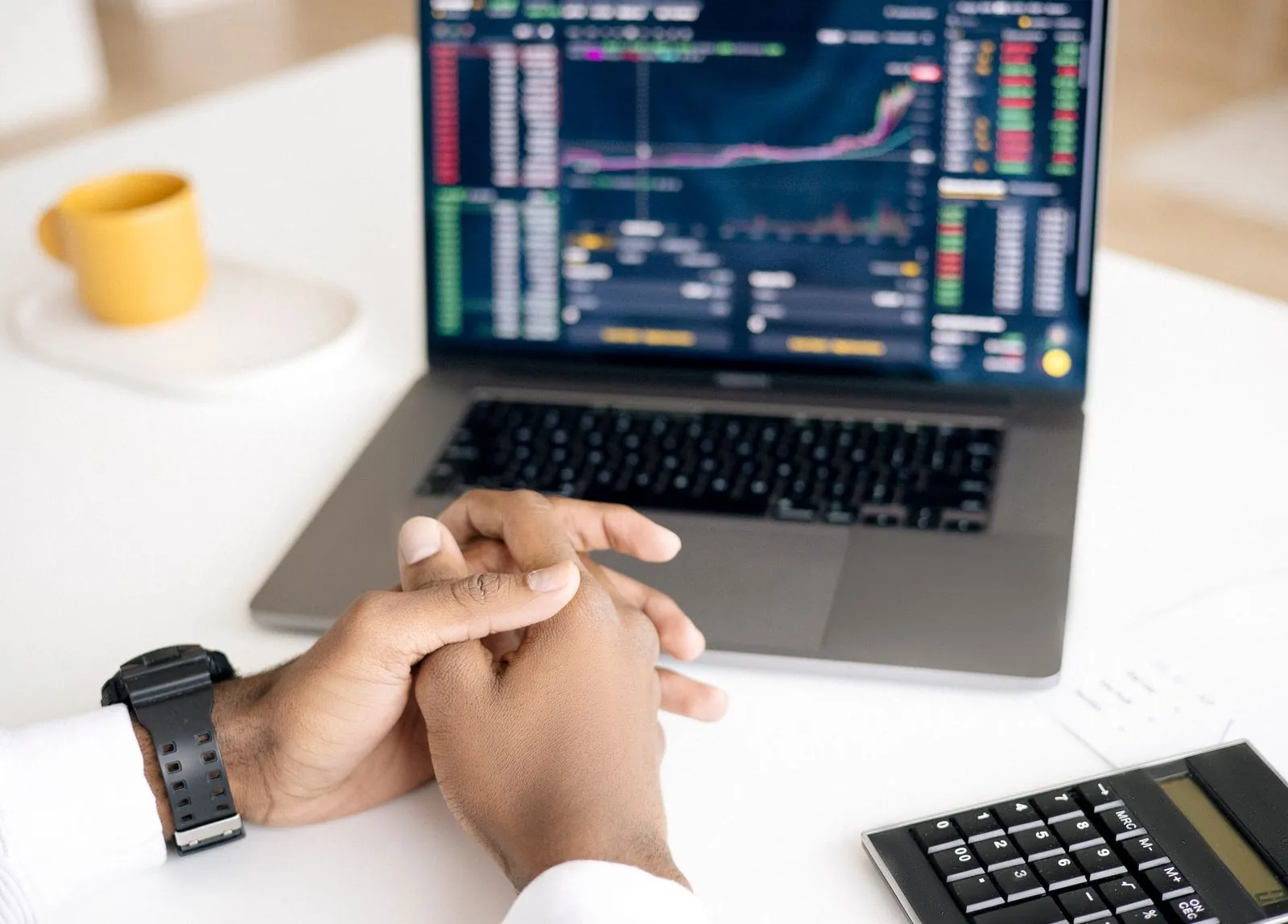 Hands clasped in front of a laptop showing charts, the moment AI decision systems hand the call to a person