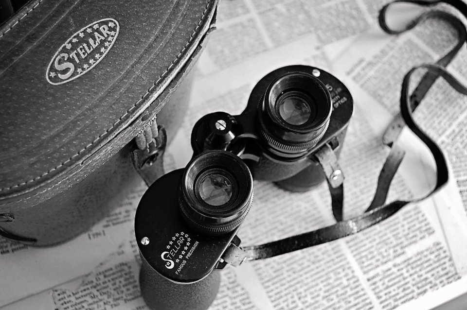 A pair of vintage binoculars resting on a folded newspaper