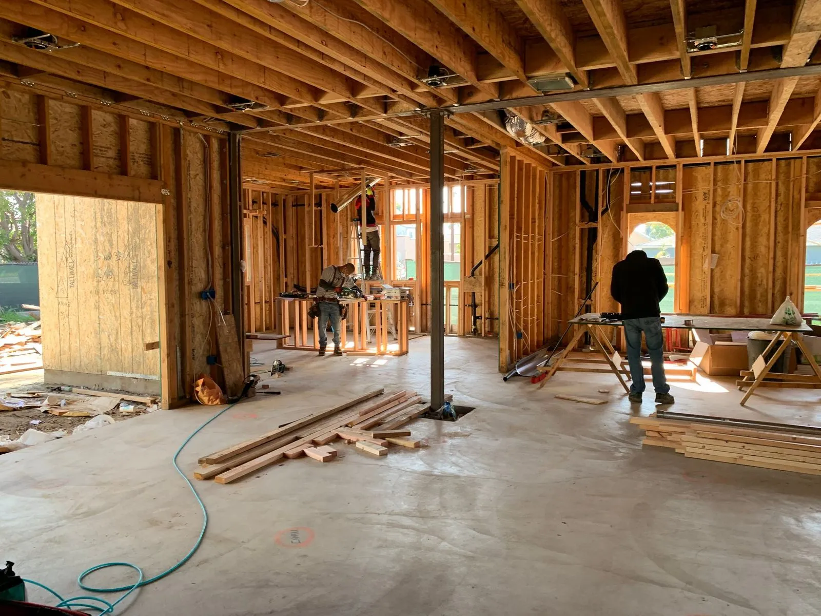 Timber framed house under construction with workers inside, the end result of a building permit