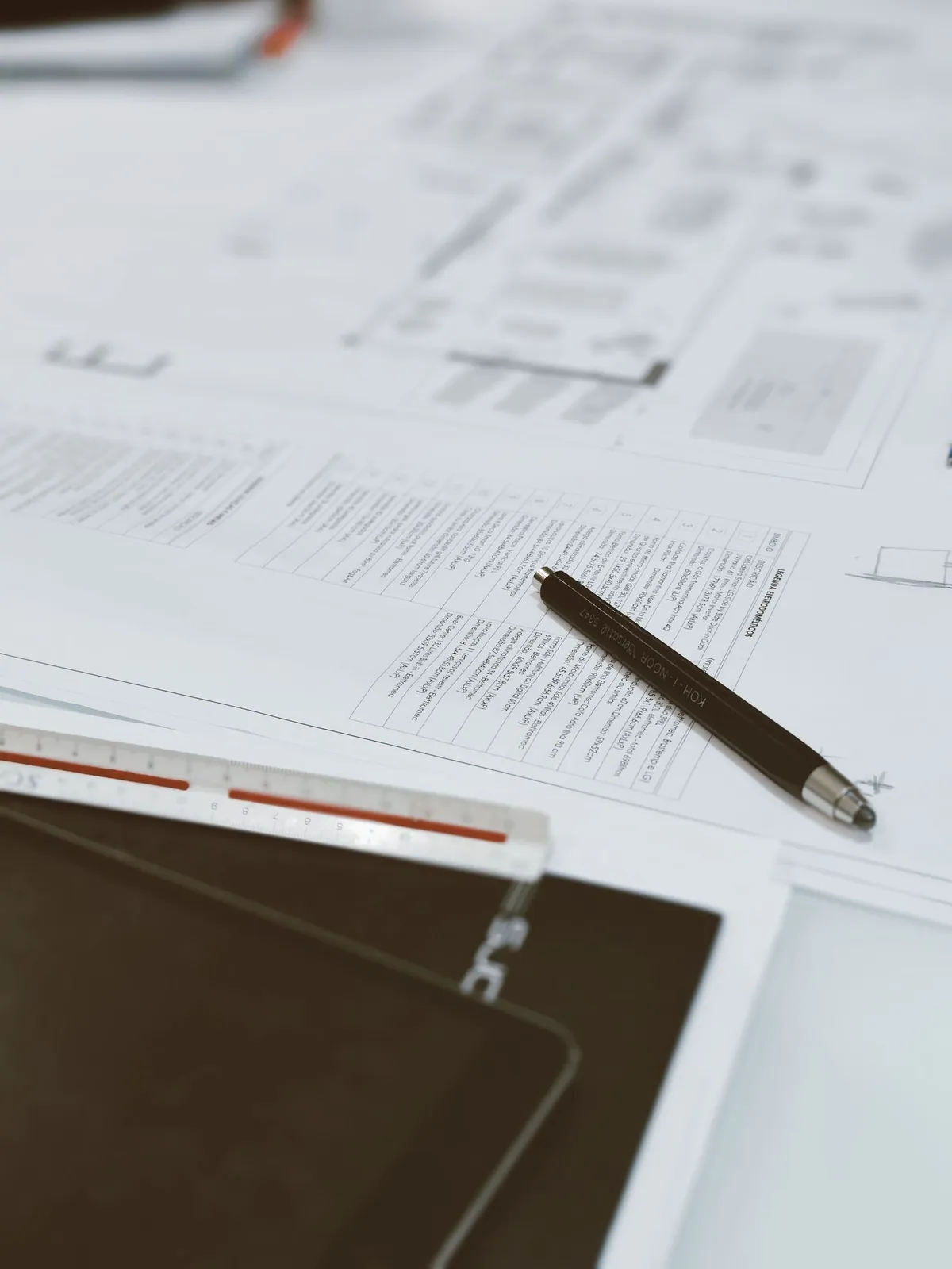 Building plans, a scale ruler and a pen on a desk ready for a building surveyor to review