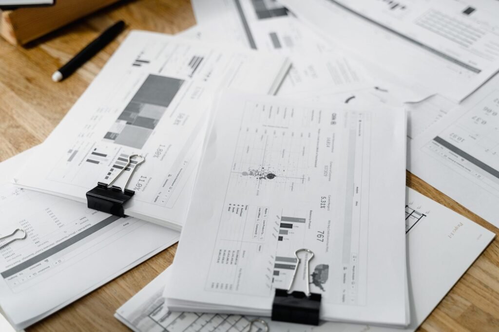 Printed reports held together with black bulldog clips on a timber desk