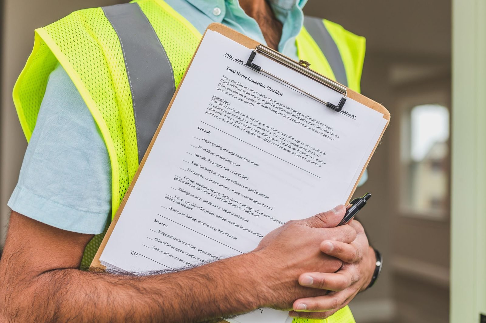 An inspector in a high visibility vest holding a clipboard checklist and pen