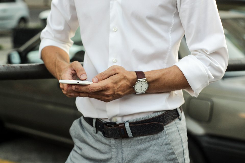 A man standing beside a vehicle filling in a form on his mobile phone