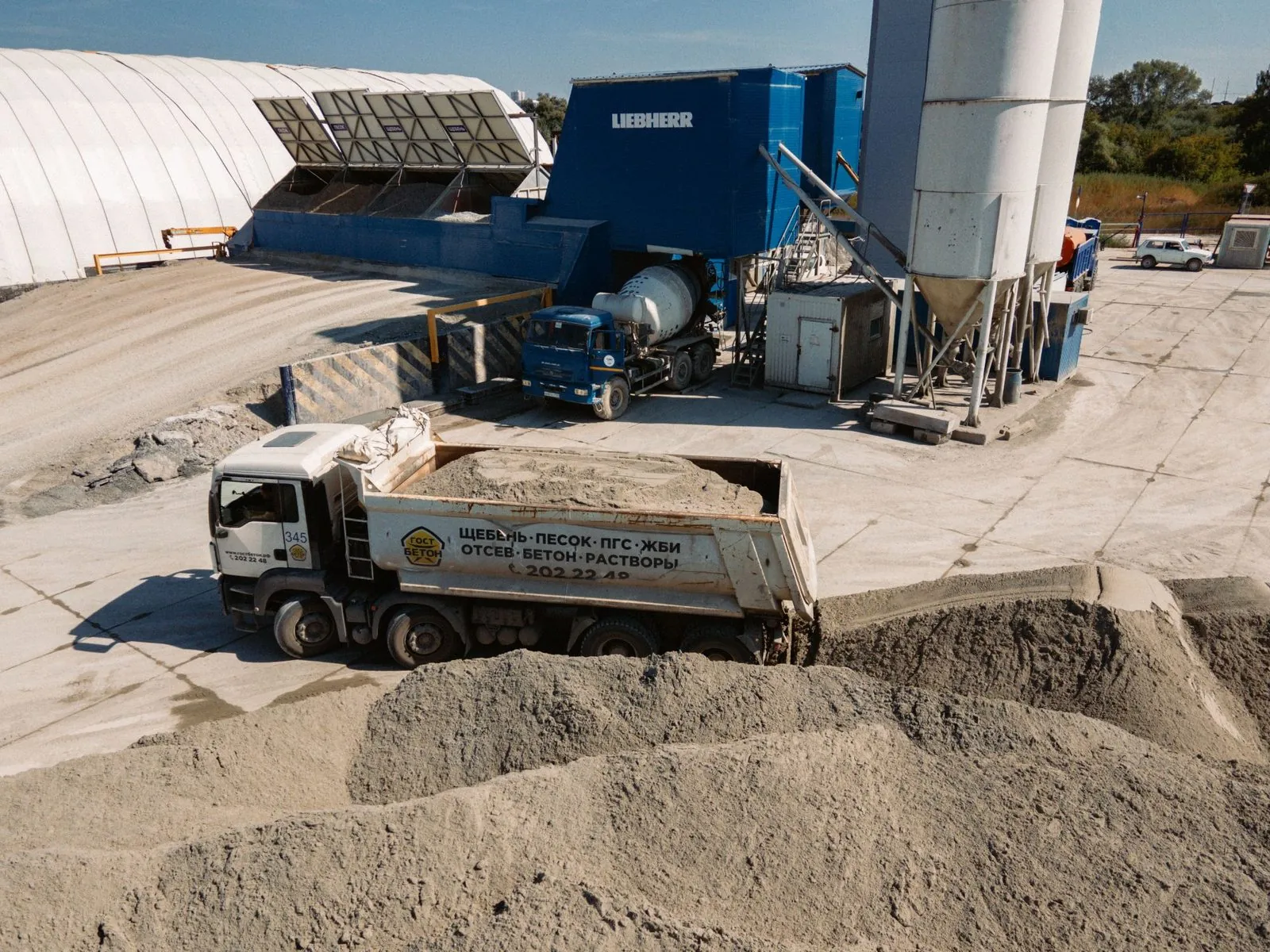 A tipper truck at a concrete batching plant beside sand and gravel stockpiles, where supplier invoice and docket extraction starts