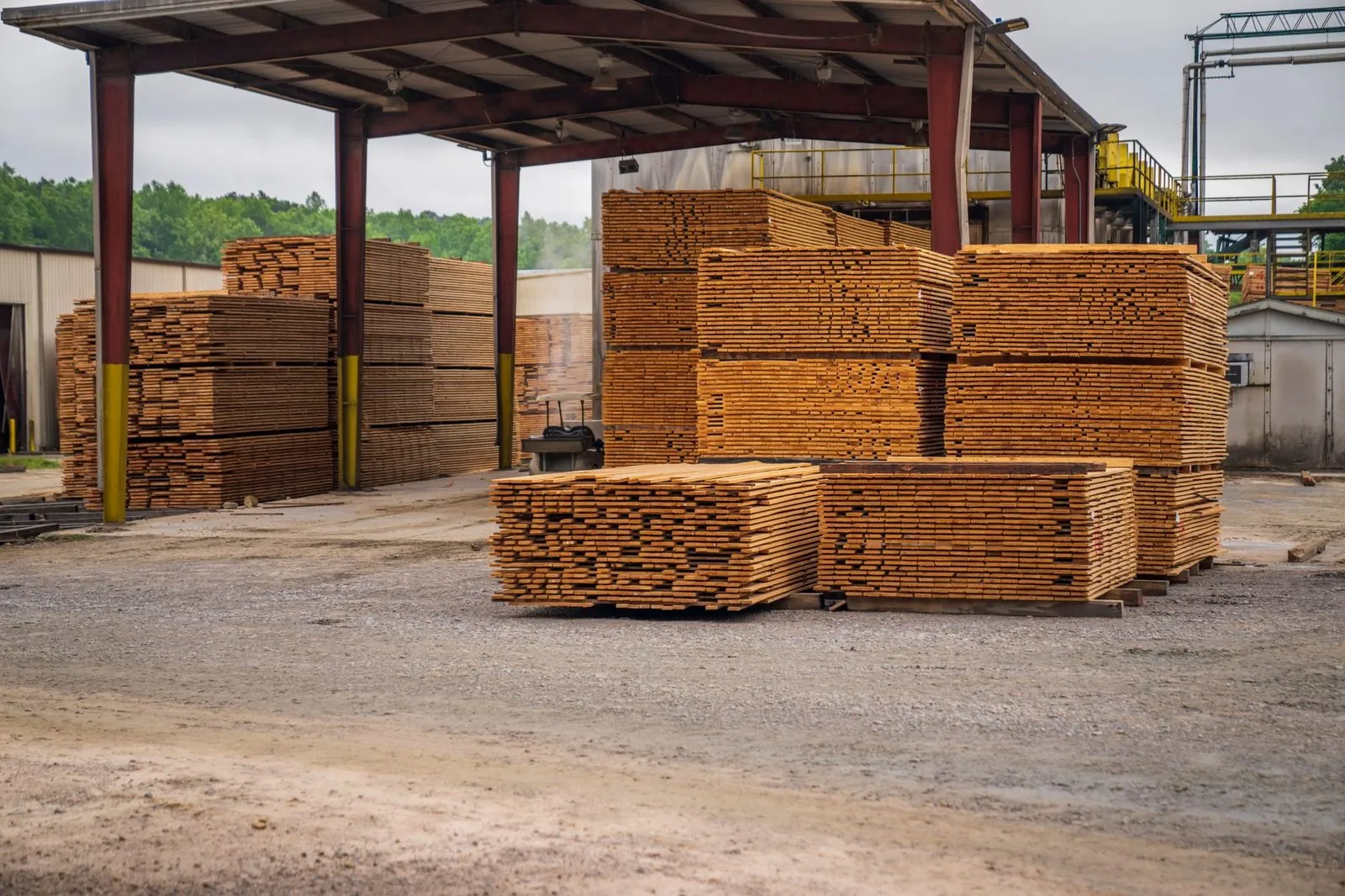 Stacks of sawn timber under an open steel shed at a supplier yard, ready for delivery