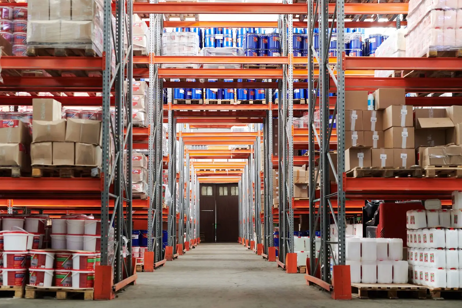 A long warehouse aisle between orange pallet racking full of boxes, ready for inventory reorder automation